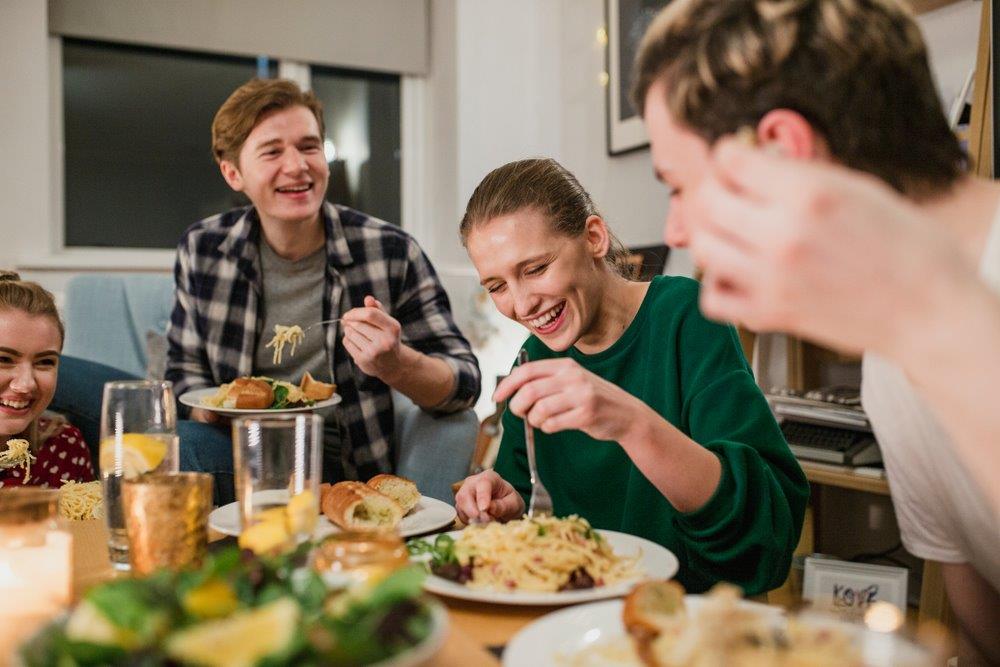 Four students laughing and enjoying a meal